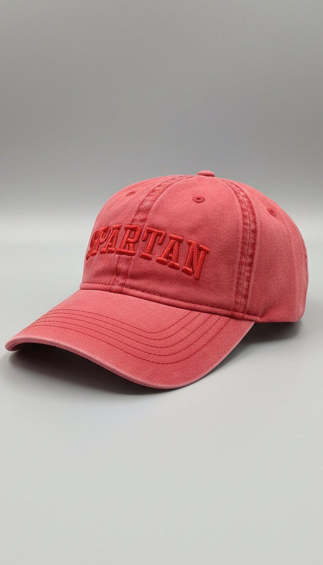 Red cap with 'SPARTAN' embroidery on a gray surface.