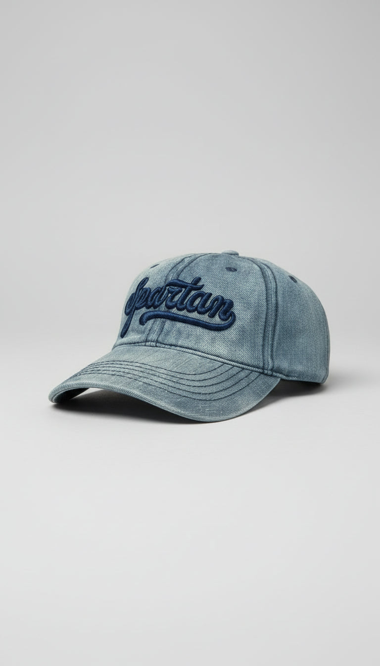 Blue denim cap with 'Spartan' embroidery on a textured black and blue jean background