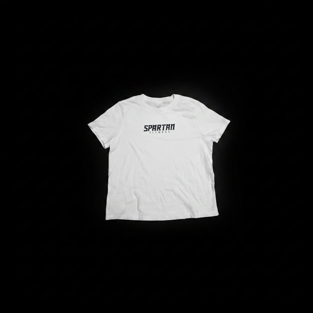A white short-sleeve crewneck t-shirt with 'SPARTAN FITNESS' printed in black across the chest, laid flat on a dark wood parquet floor.
