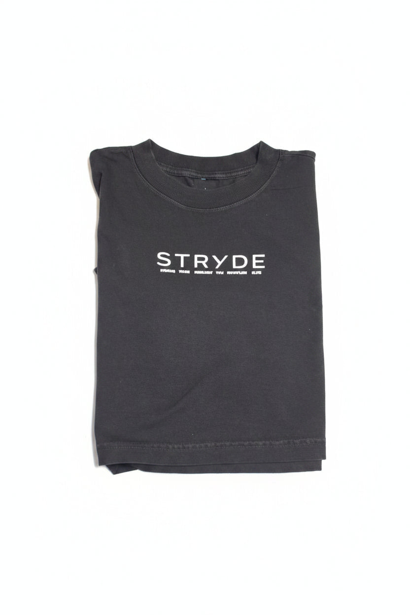 A dark gray crewneck t-shirt with 'STRYDE' printed vertically in white on the front, laid flat on a polished wood table.